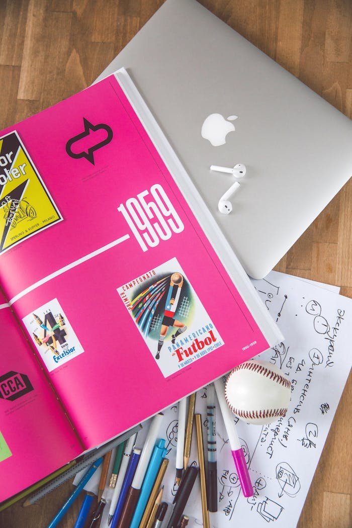 project-02-d A creative workspace featuring a colorful open book, laptop, and drawing materials, ideal for design inspiration.