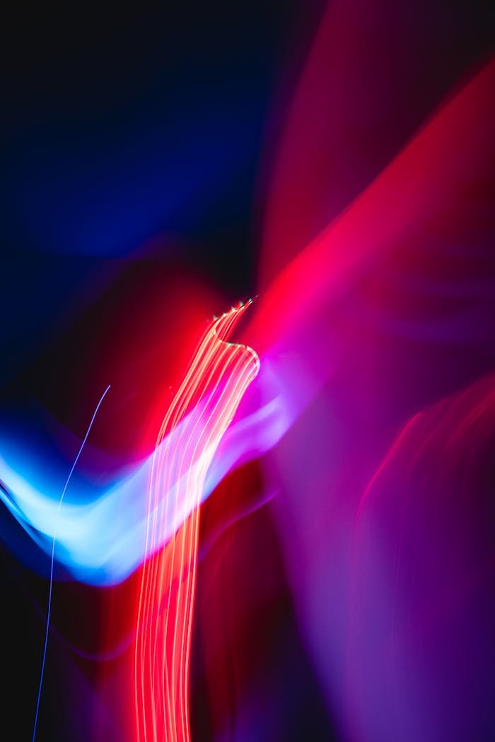 services-01 Vibrant abstract image with dynamic red and blue light streaks over a dark background.